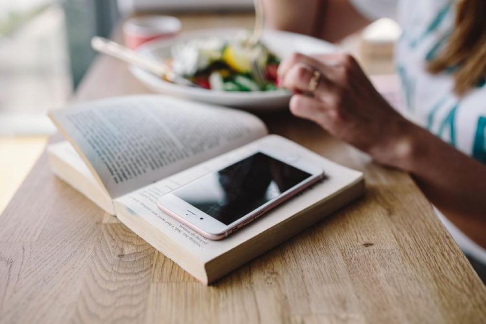 Woman eating breakfast and reading a book Woman eating breakfast and reading a book