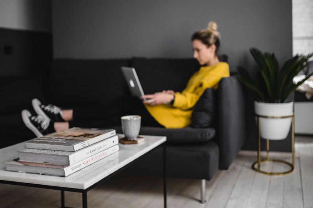 Young woman sitting on the sofa and working on her laptop Young woman sitting on the sofa and working on her laptop