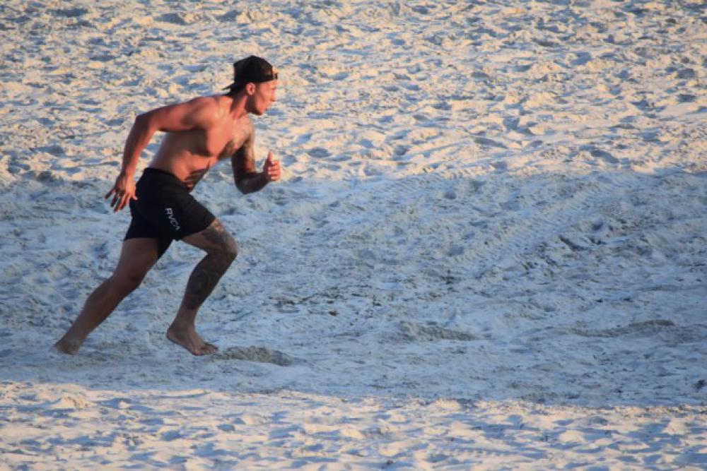 Young millennial male running on the beach Young millennial male running on the beach