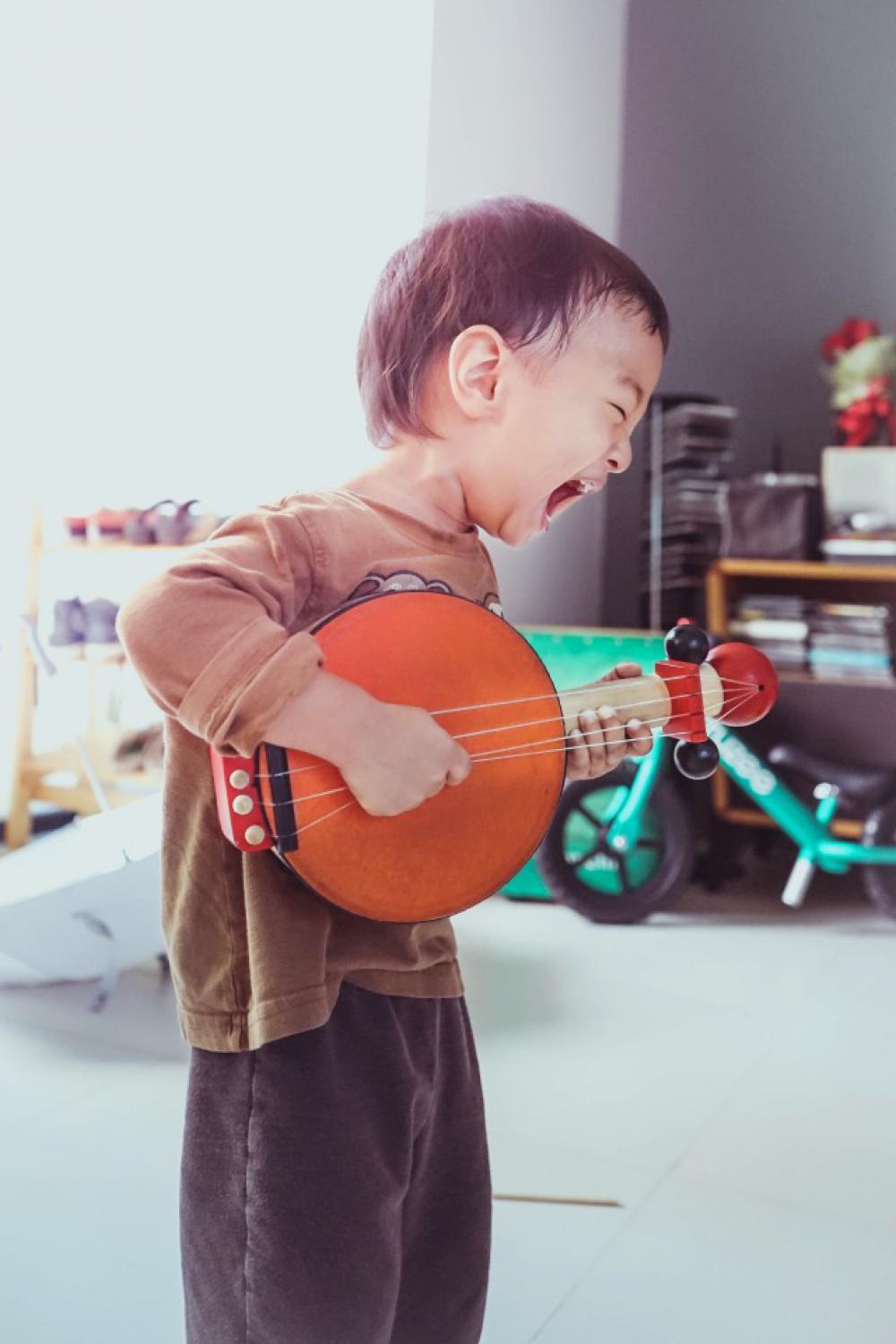 A boy is playing toy guitar. A boy is playing toy guitar.
