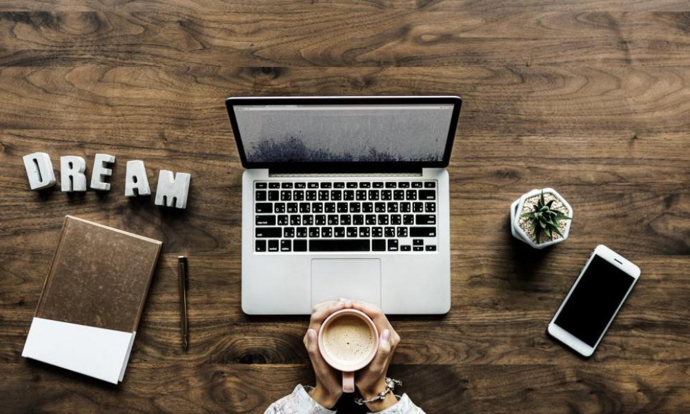 Flat lay of a laptop and hands holding a coffee mug Flat lay of a laptop and hands holding a coffee mug