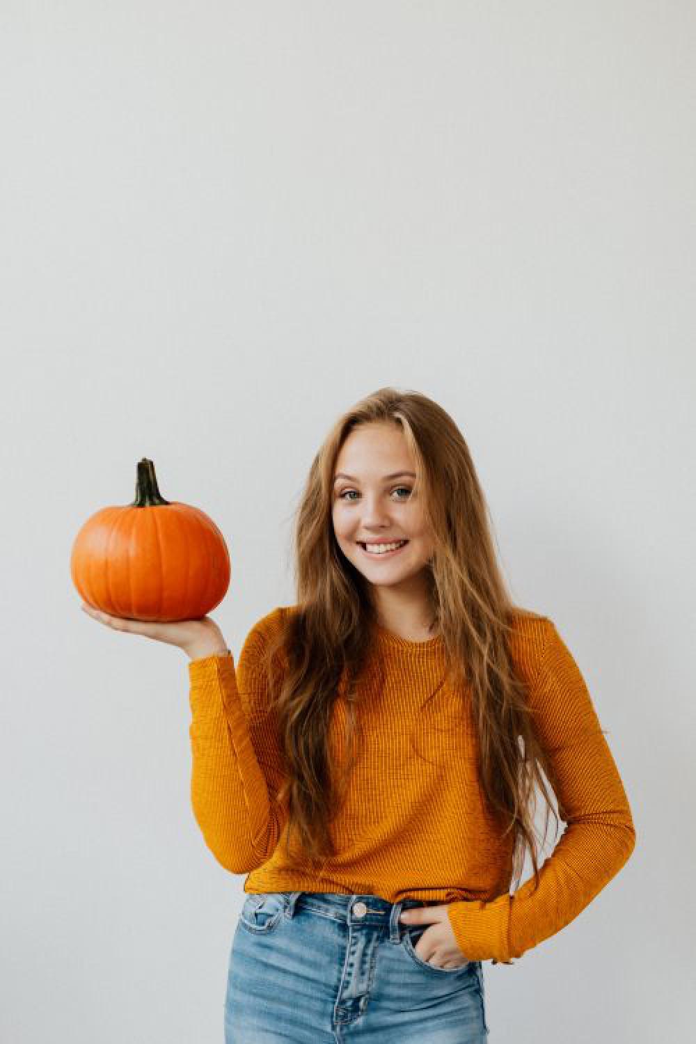 A young girl holds a pumpkin in her hand A young girl holds a pumpkin in her hand