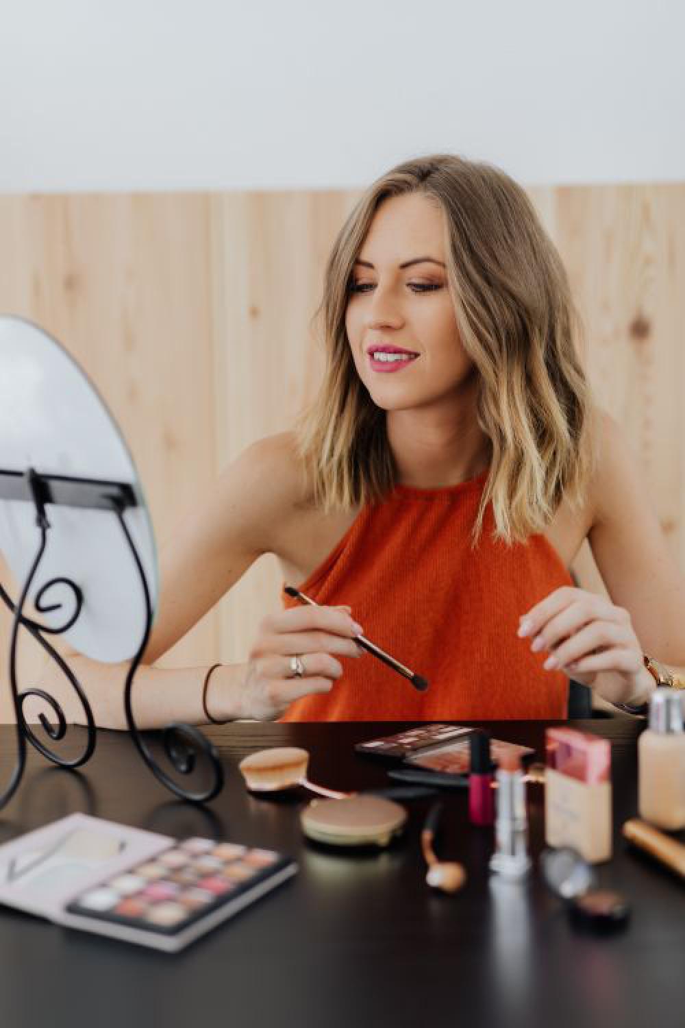 Young woman sitting and doing makeup in front of mirror Young woman sitting and doing makeup in front of mirror