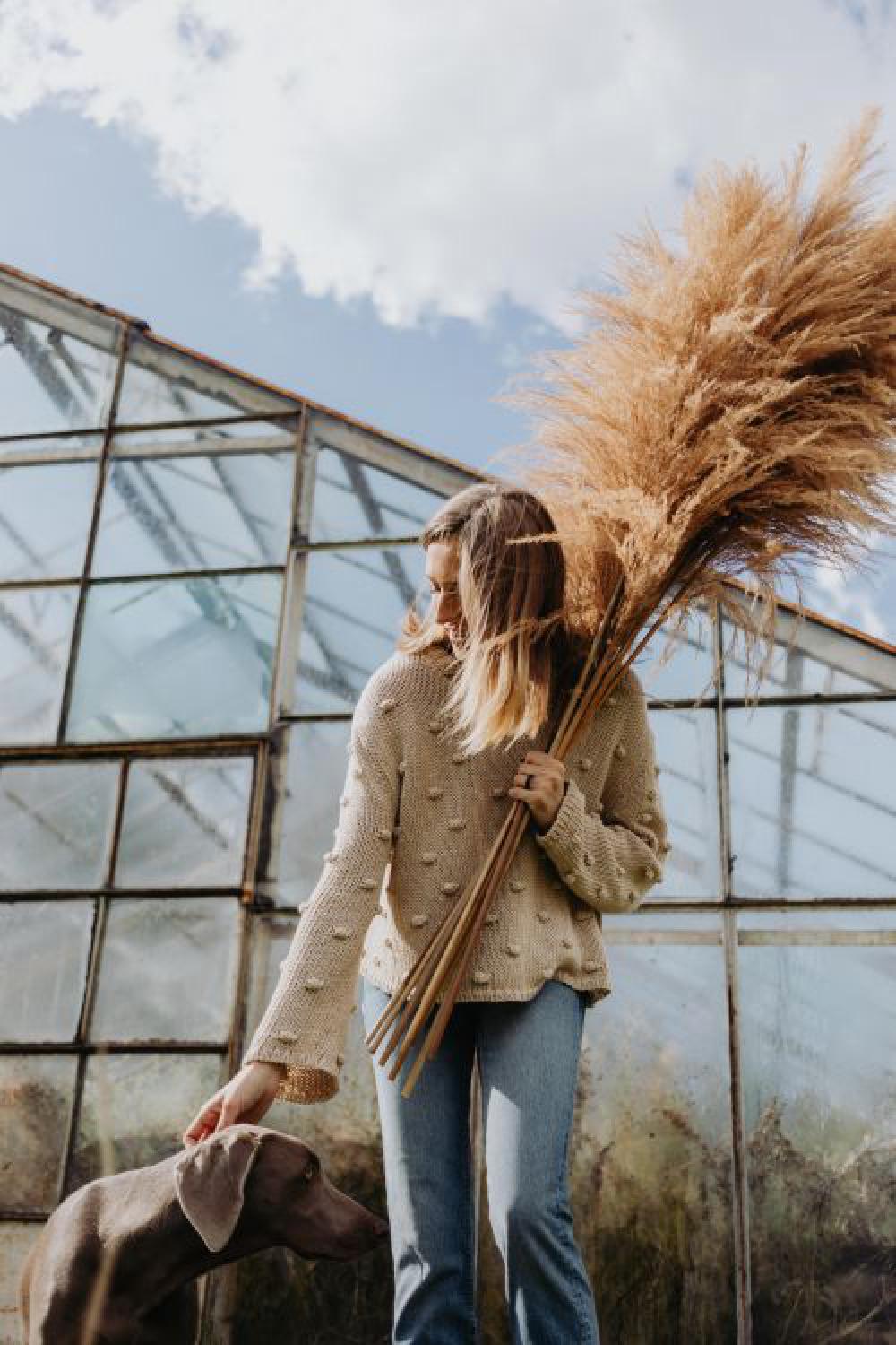The woman is holding the pampas grass The woman is holding the pampas grass