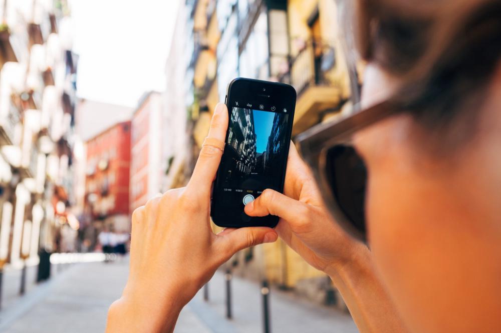 A Woman Snaps A Photo On Her Mobile Phone Up A Sunny Street Photo A Woman Snaps A Photo On Her Mobile Phone Up A Sunny Street Photo