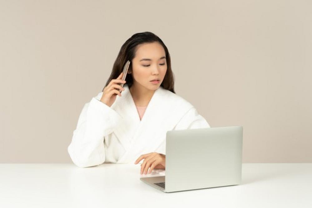 Young Asian Woman Talking On The Phone While Doing Online Shopping Young Asian Woman Talking On The Phone While Doing Online Shopping