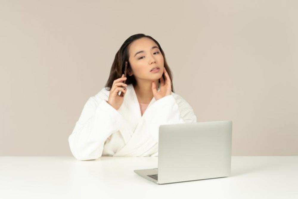 Young Asian Woman Talking On The Phone While Doing Online Shopping Young Asian Woman Talking On The Phone While Doing Online Shopping