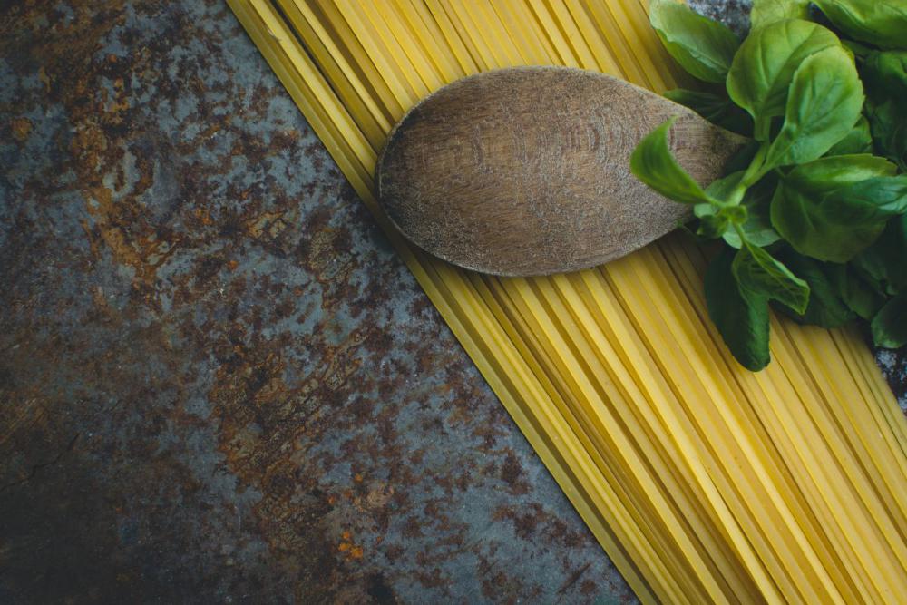 Pasta spaghetti with basil and wooden spoon on a rusty metallic background Pasta spaghetti with basil and wooden spoon on a rusty metallic background