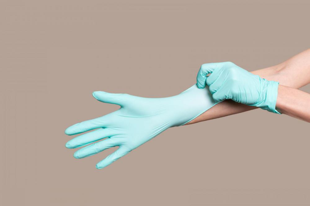 Woman hands putting on a latex gloves Woman hands putting on a latex gloves