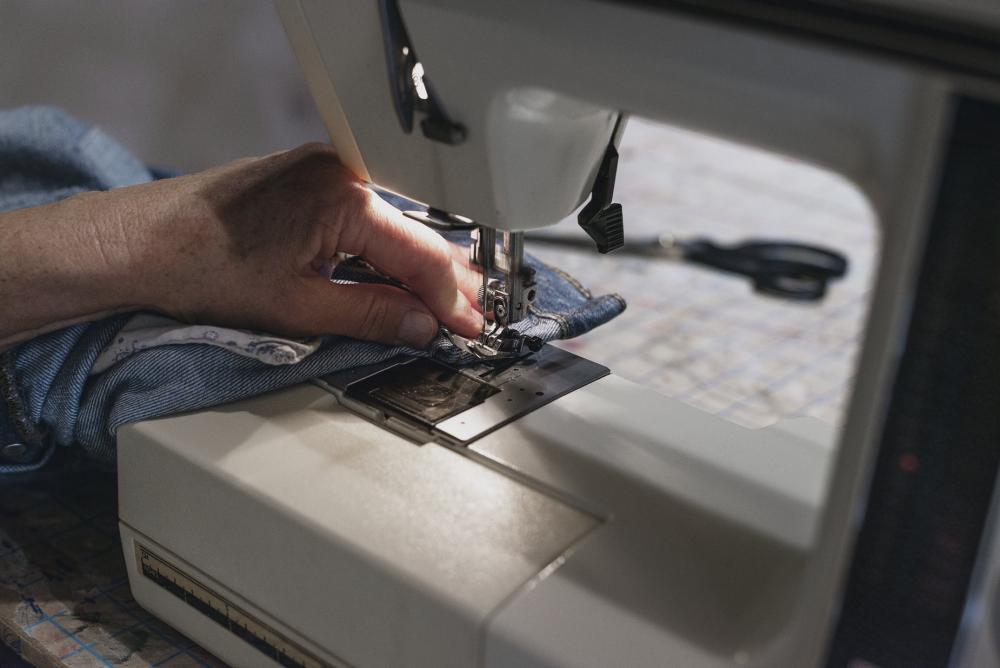 Hand Uses Sewing Machine On Denim Photo Hand Uses Sewing Machine On Denim Photo