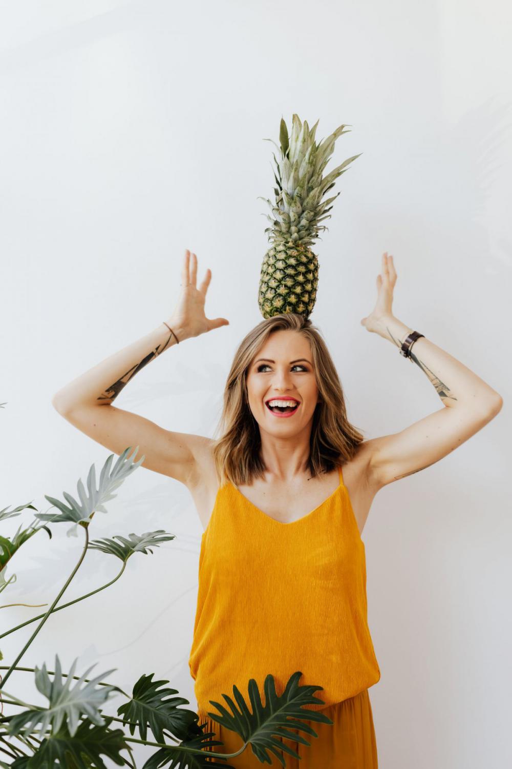 A beautiful smiling young woman is holding a pineapple A beautiful smiling young woman is holding a pineapple