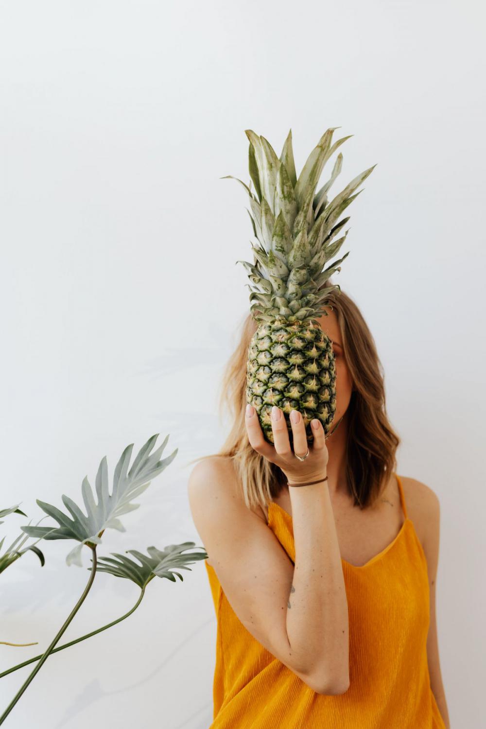 A beautiful smiling young woman is holding a pineapple A beautiful smiling young woman is holding a pineapple