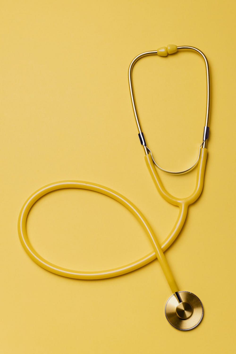 Yellow stethoscope and pills on yellow background Yellow stethoscope and pills on yellow background