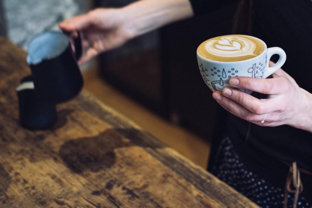 Barista holding a cup with coffee cappuccino Barista holding a cup with coffee cappuccino