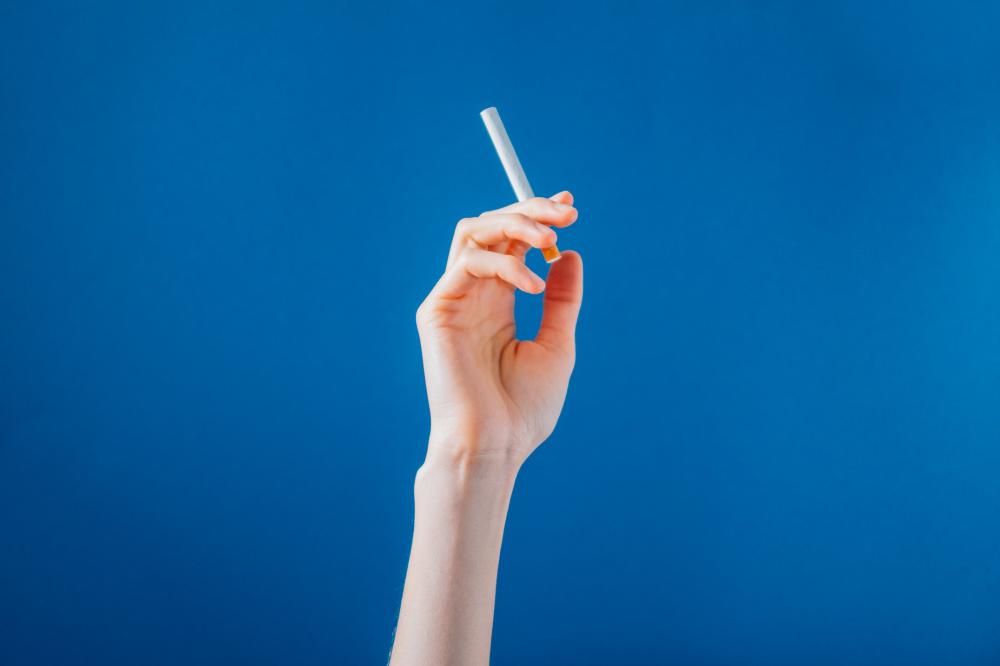 AHand Holding A Cigarette On Blue Background Photo AHand Holding A Cigarette On Blue Background Photo