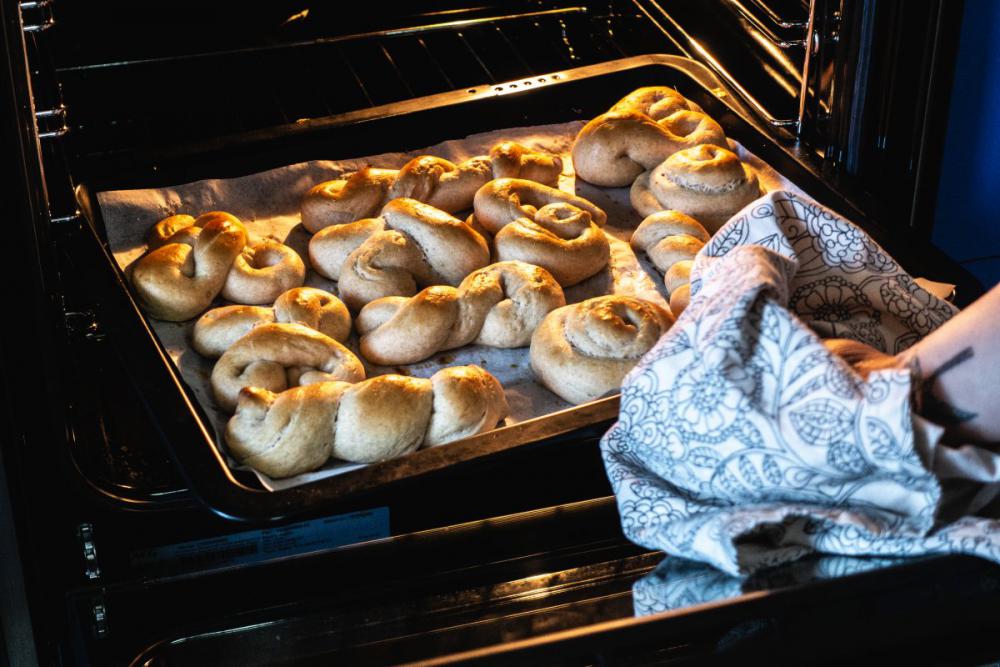 Woman taking out homemade baked dessert from oven Woman taking out homemade baked dessert from oven