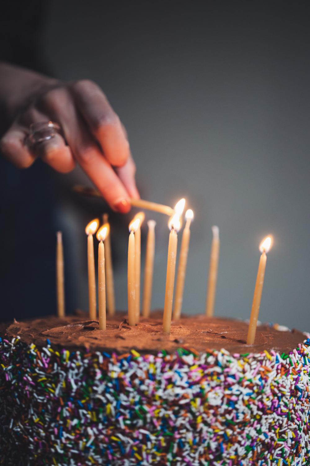 Womans Hand Liting Birthday Candles Photo Womans Hand Liting Birthday Candles Photo