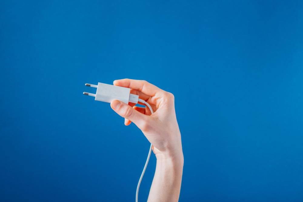 Holding A White Phone Charger On Blue Photo Holding A White Phone Charger On Blue Photo
