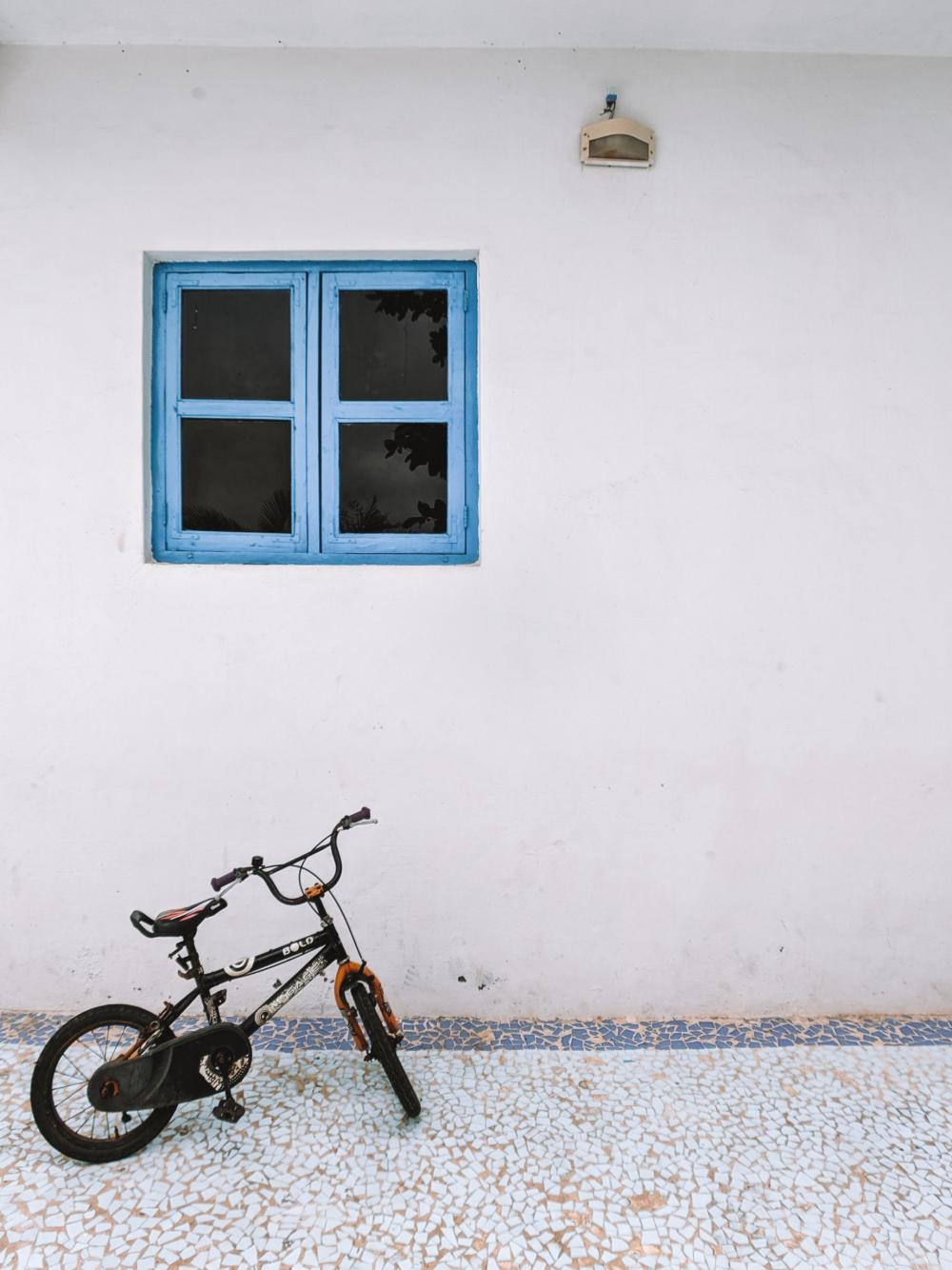 Small Bike Under Blue Window Frame Photo Small Bike Under Blue Window Frame Photo