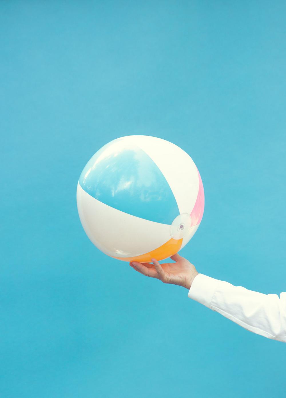 Hand Holds Up A Bright Beach Ball Photo Hand Holds Up A Bright Beach Ball Photo