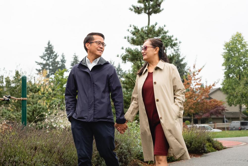 Couple Holds Hands As They Walk Through Park Photo Couple Holds Hands As They Walk Through Park Photo