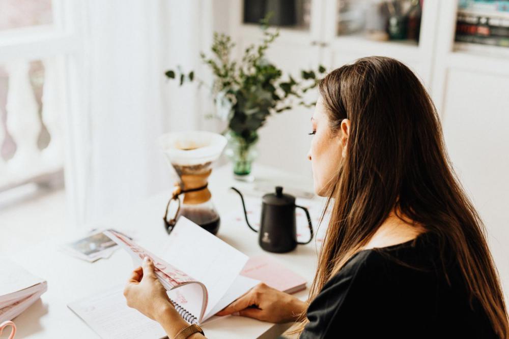 The woman drinks coffee and works at her desk The woman drinks coffee and works at her desk