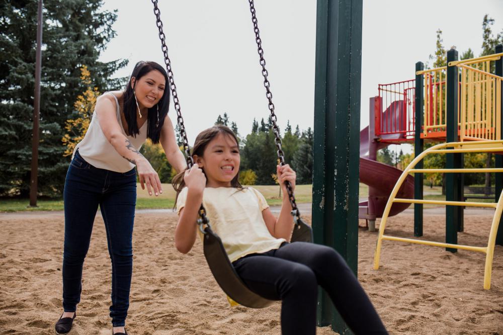Woman Plays With Child On Swing Set Photo Woman Plays With Child On Swing Set Photo