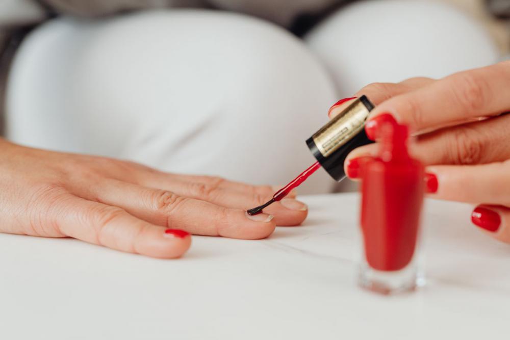 Closeup of a woman painting her nails with red nail polish Closeup of a woman painting her nails with red nail polish