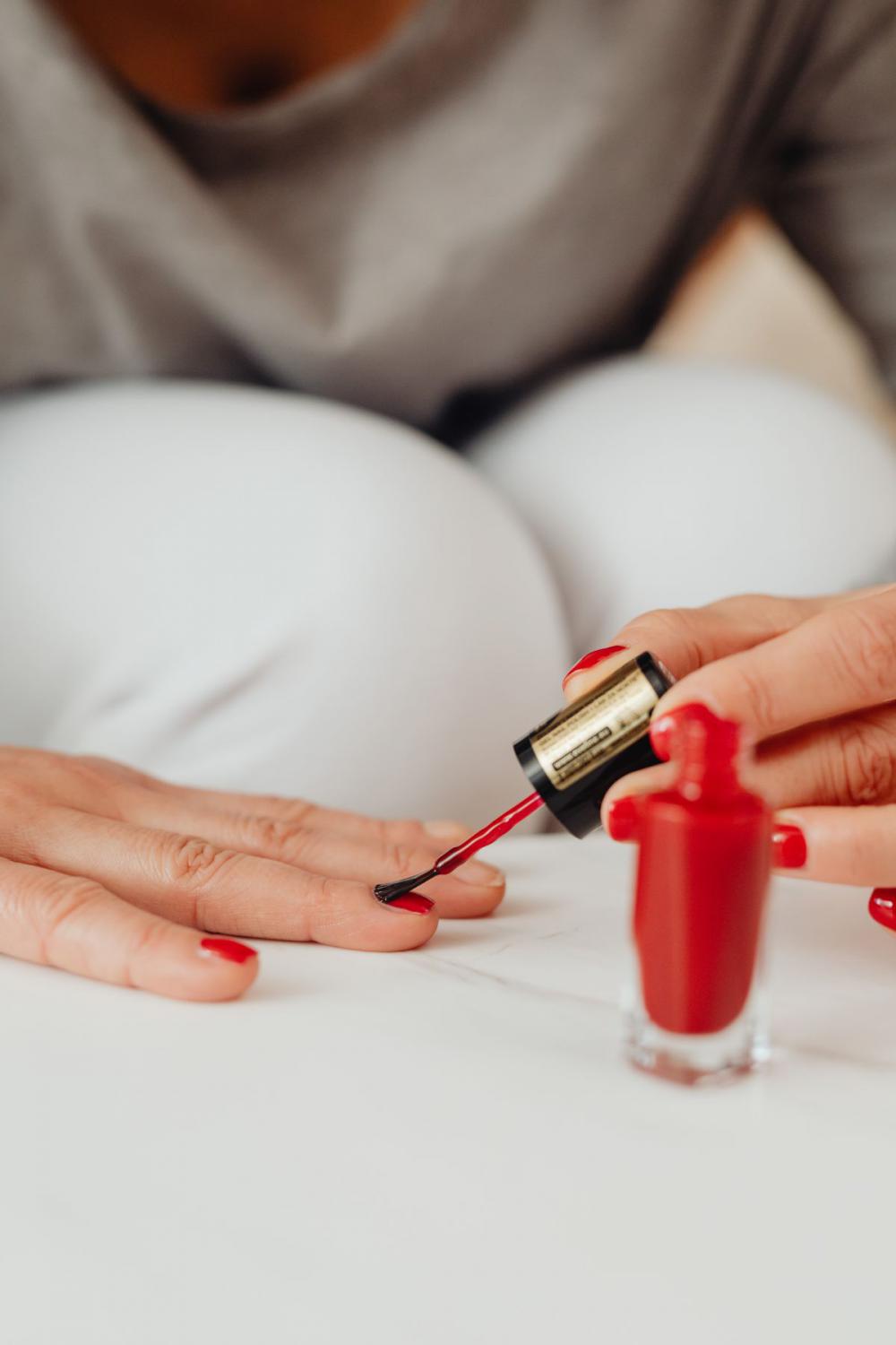 Closeup of a woman painting her nails with red nail polish Closeup of a woman painting her nails with red nail polish