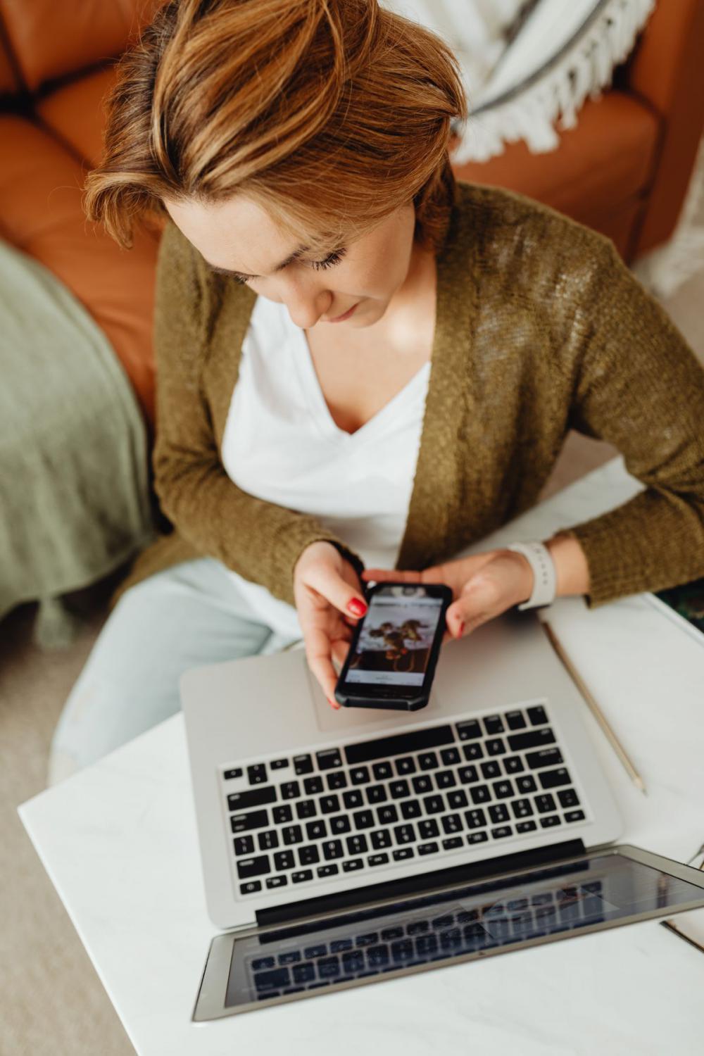 A woman works using a laptop from her couch at home A woman works using a laptop from her couch at home