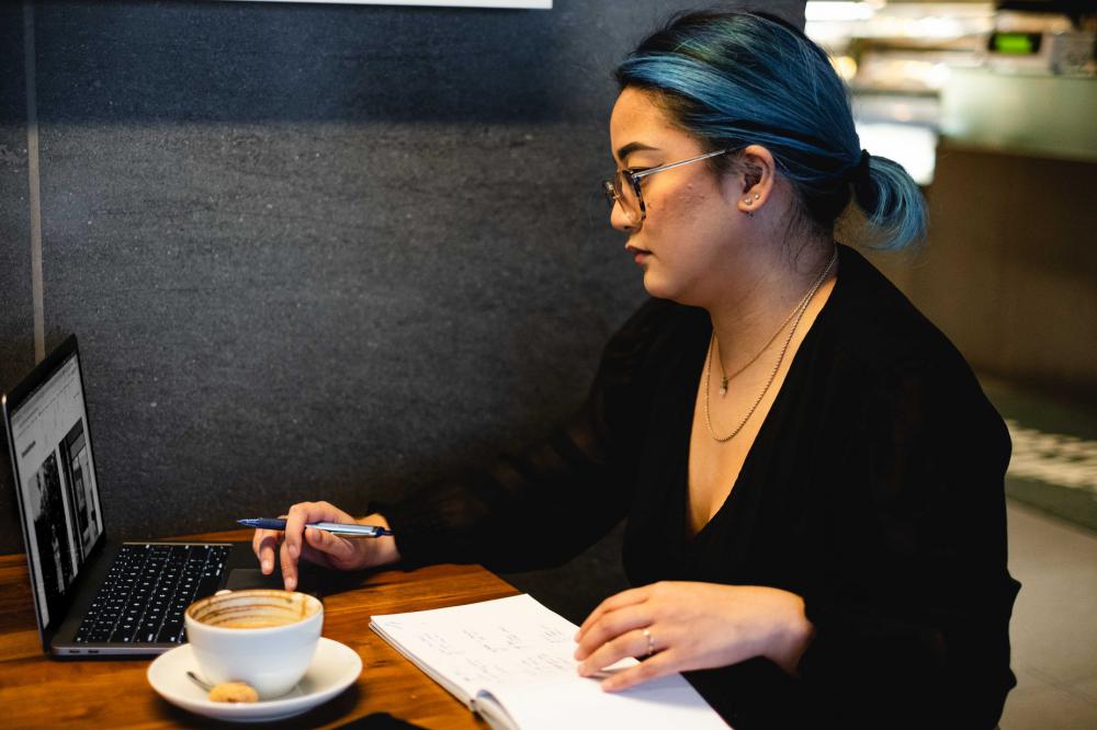Woman Sits Alone In A Quiet Cafe With A Notebook And Laptop Photo Woman Sits Alone In A Quiet Cafe With A Notebook And Laptop Photo