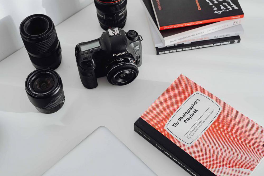 Photographer's desk - books, DSLR camera and lenses Photographer's desk - books, DSLR camera and lenses