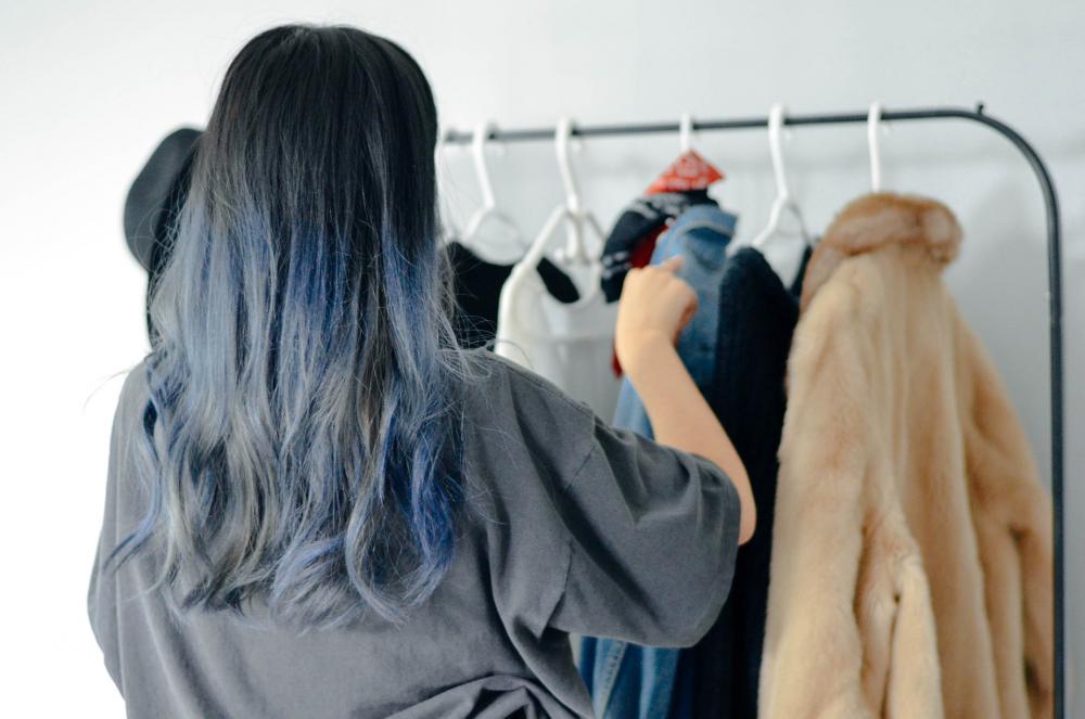 Person Organizes Clothes On A Thin Clothing Rack Photo Person Organizes Clothes On A Thin Clothing Rack Photo