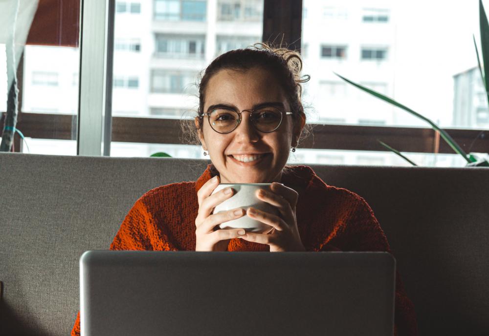Women Smiles Holding Mug Sitting Behind A Laptop Photo Women Smiles Holding Mug Sitting Behind A Laptop Photo