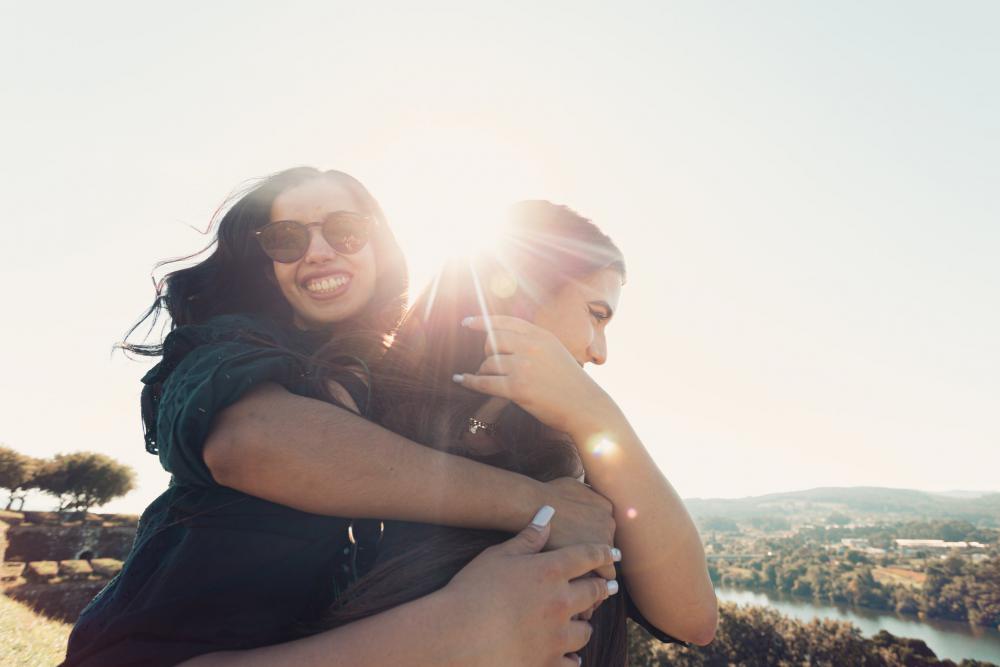 Woman Smiles And Hugs A Woman From Behind Photo Woman Smiles And Hugs A Woman From Behind Photo