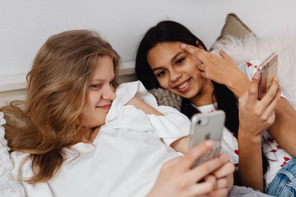 Teens sit together on the couch and use phones Teens sit together on the couch and use phones