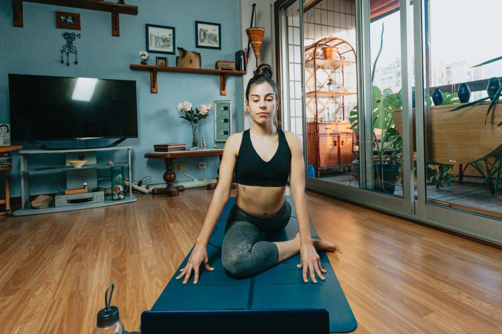Woman Sits In A Yoga Pose In Their Living Room Photo Woman Sits In A Yoga Pose In Their Living Room Photo