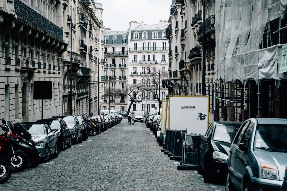 Cobblestone Street With Tall Buildings And Cars Photo Cobblestone Street With Tall Buildings And Cars Photo