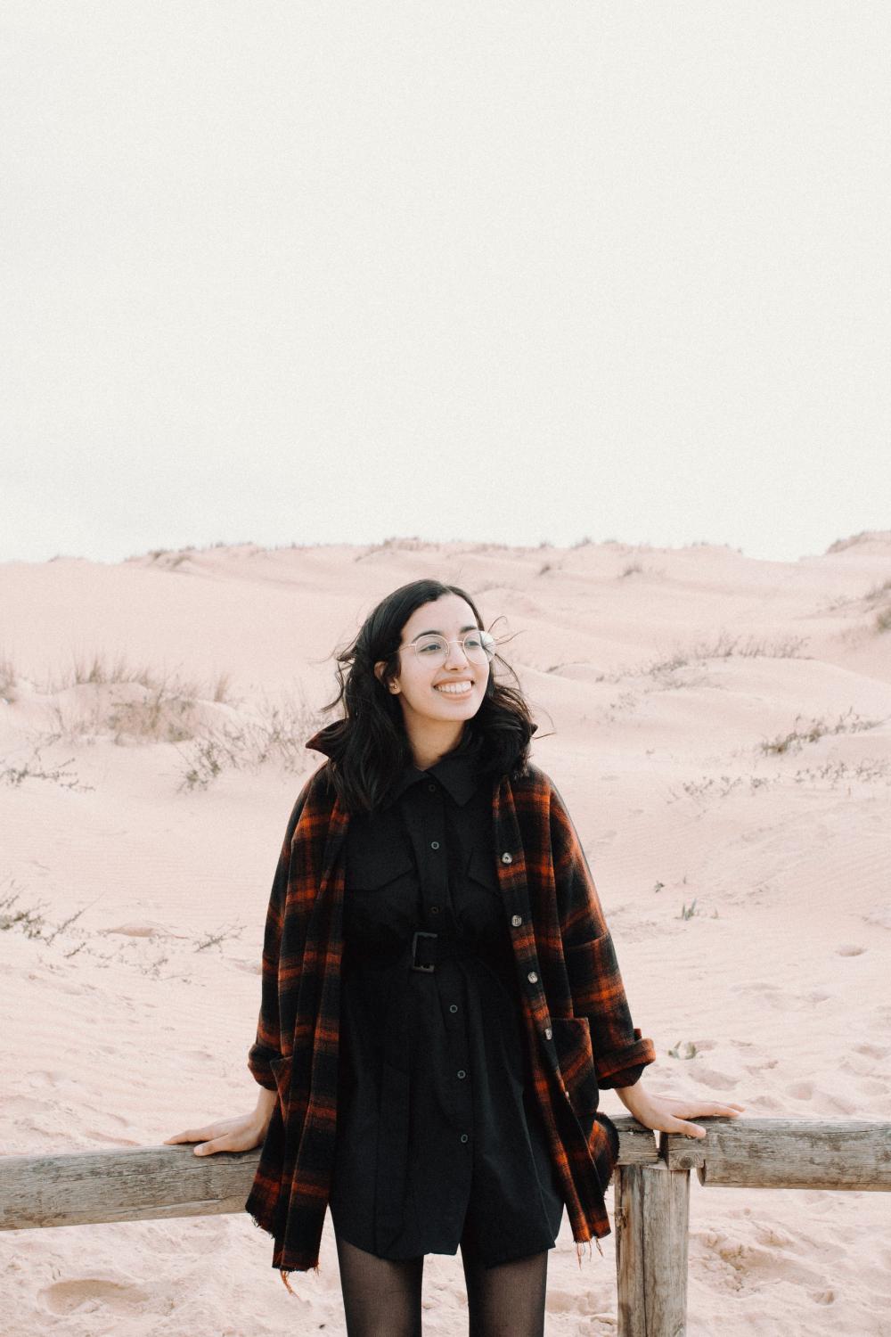 Woman Smiles And Stands In Front Of Sandy Hills Photo Woman Smiles And Stands In Front Of Sandy Hills Photo