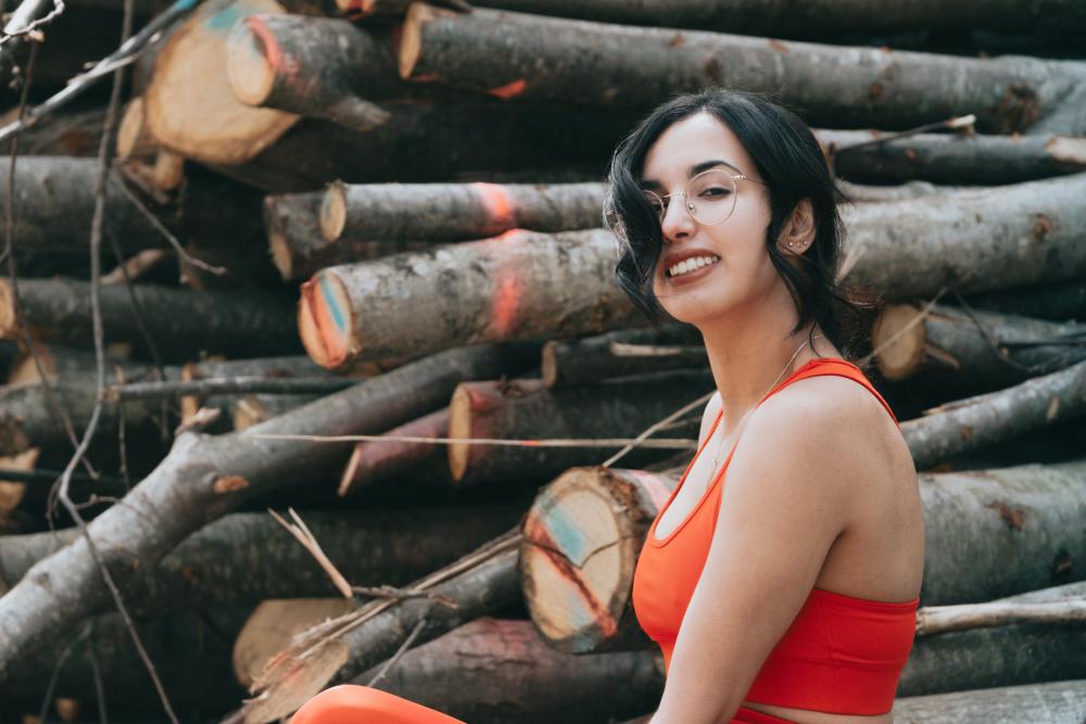 Woman Smiles At The Camera While Standing Wood Stack Photo Woman Smiles At The Camera While Standing Wood Stack Photo