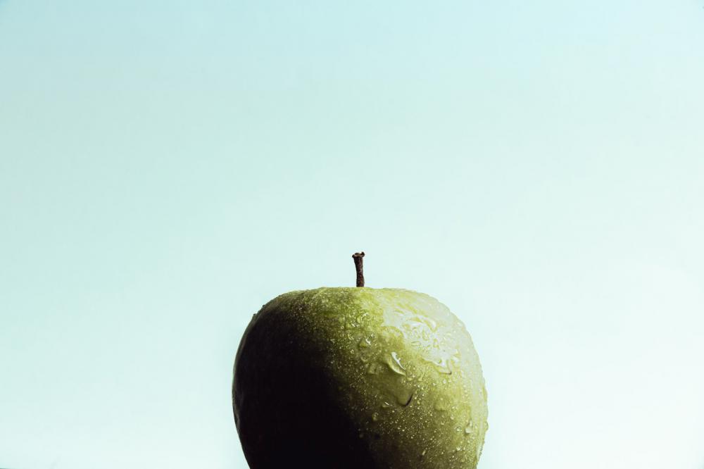 A Wet Crisp Green Apple Against A Light Blue Background Photo A Wet Crisp Green Apple Against A Light Blue Background Photo
