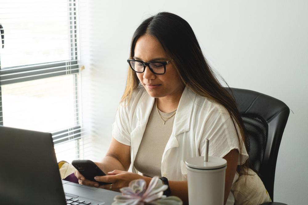 Person Sits At Their Desk And Looks At Their Cell Phone Photo Person Sits At Their Desk And Looks At Their Cell Phone Photo