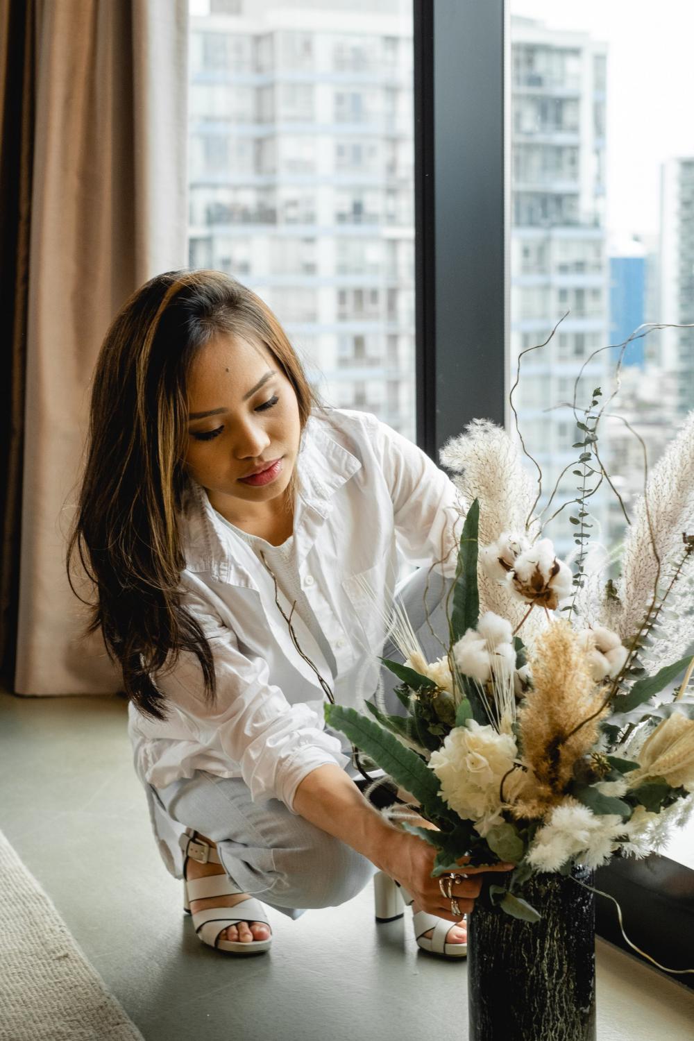 Woman Crouches To Arrange Flowers In A Vase Photo Woman Crouches To Arrange Flowers In A Vase Photo