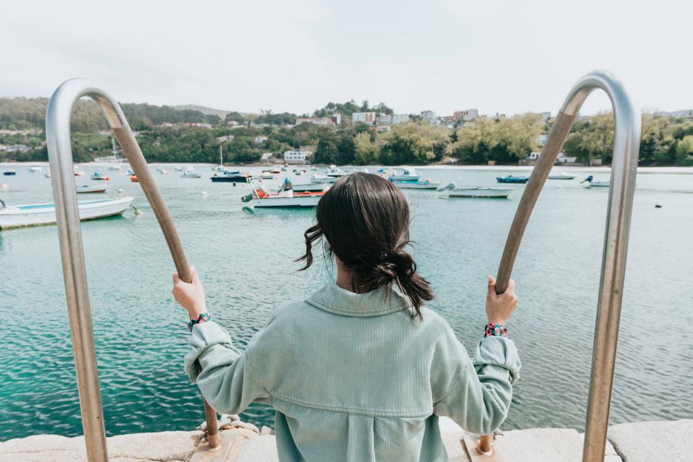 Person Outdoors Looks Out At Boats Below Photo Person Outdoors Looks Out At Boats Below Photo