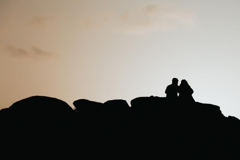 Silhouetted People Sitting On Rocks By The Setting Sun Photo Silhouetted People Sitting On Rocks By The Setting Sun Photo