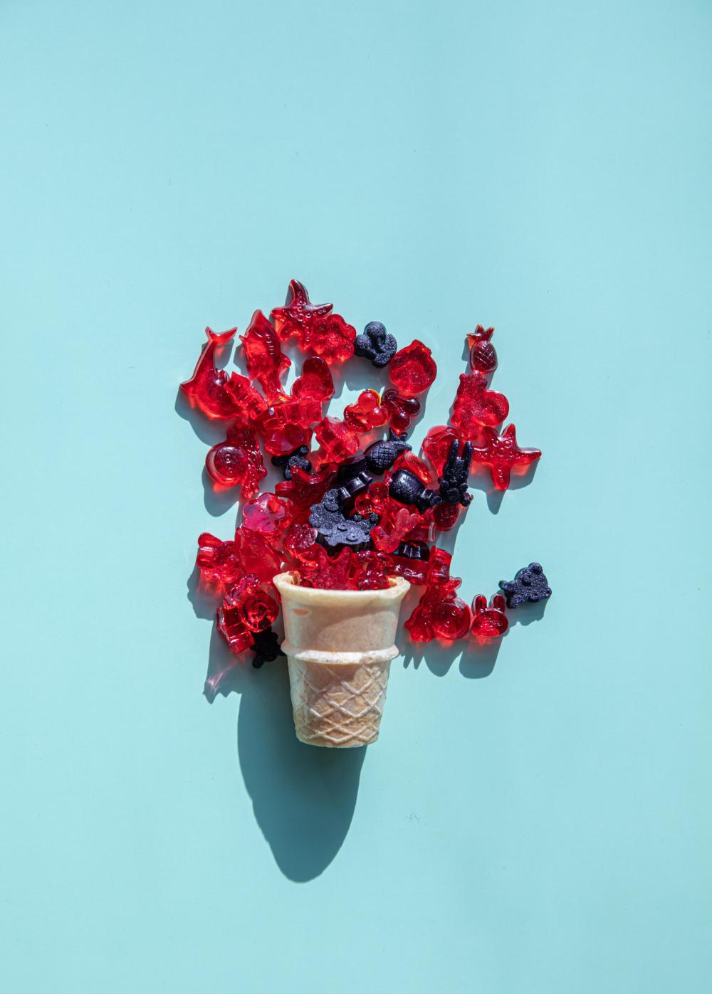 Icecream Cone With Candy Spilling Out On Blue Background Photo Icecream Cone With Candy Spilling Out On Blue Background Photo