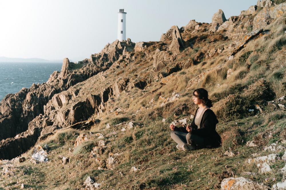 Woman Sits On The Side Of A Hill Above Water Photo Woman Sits On The Side Of A Hill Above Water Photo