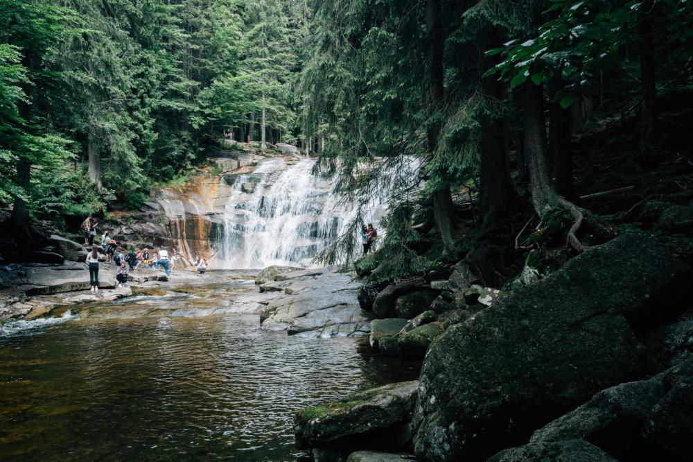 People Enjoy The Cool Water From A Forest Lined Waterfall Photo People Enjoy The Cool Water From A Forest Lined Waterfall Photo