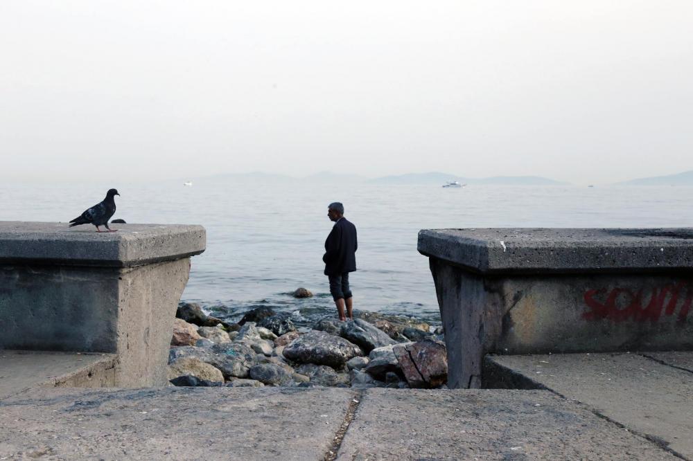 Person Stands Barefoot On A Rocky Shore Looking Out Photo Person Stands Barefoot On A Rocky Shore Looking Out Photo
