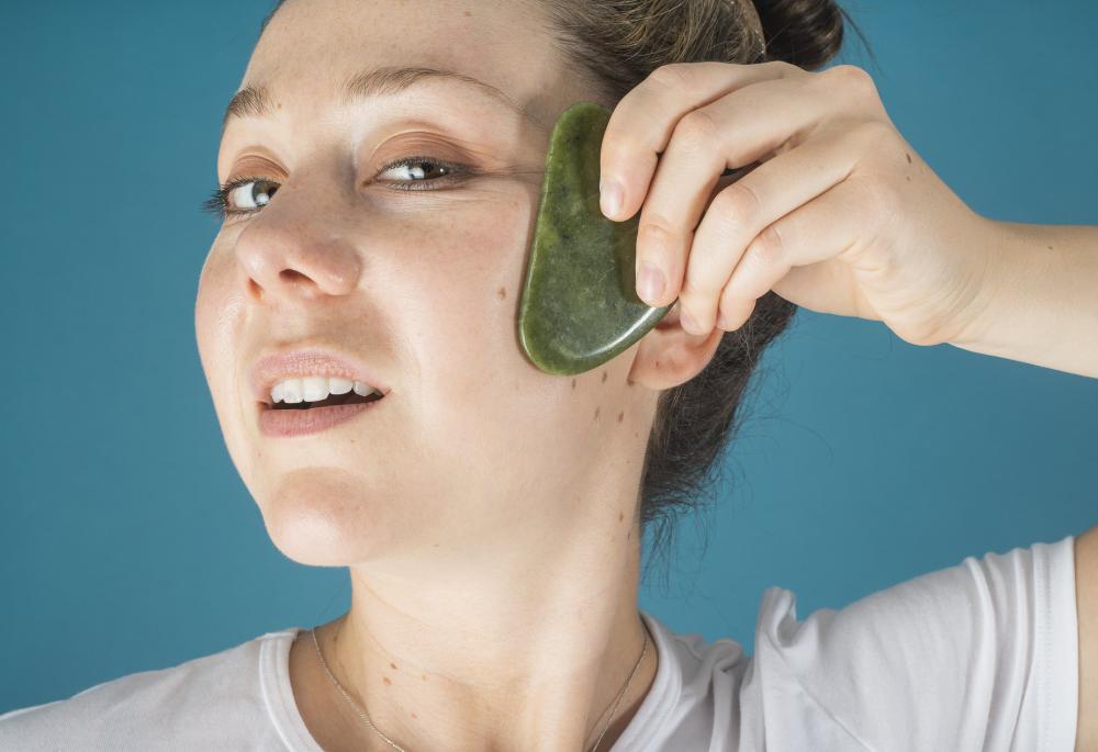Woman Holds A Jade Face Massager To Her Face Photo Woman Holds A Jade Face Massager To Her Face Photo